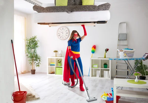 Strong super housewife cleaning home and holding bad in the air