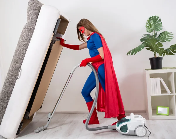 Femme super héros passer l'aspirateur sous le lit — Photo