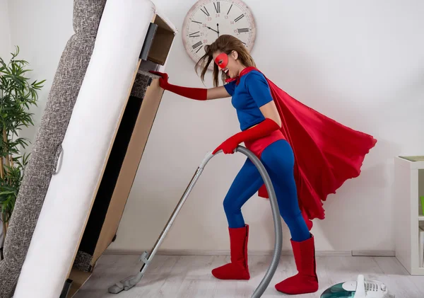 Wanita cantik superhero menyedot debu di bawah tempat tidur — Stok Foto