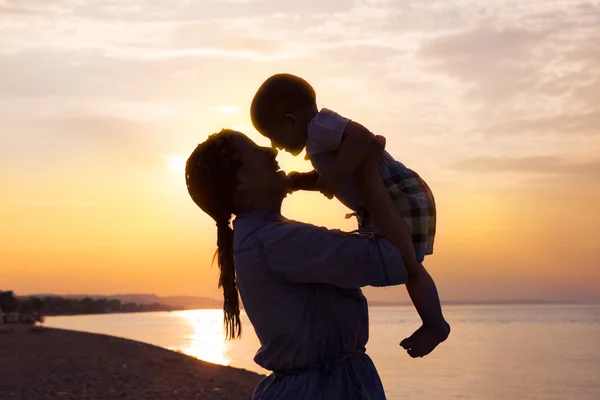 Lykkelig familiemor og sønn på stranden ved solnedgang – stockfoto