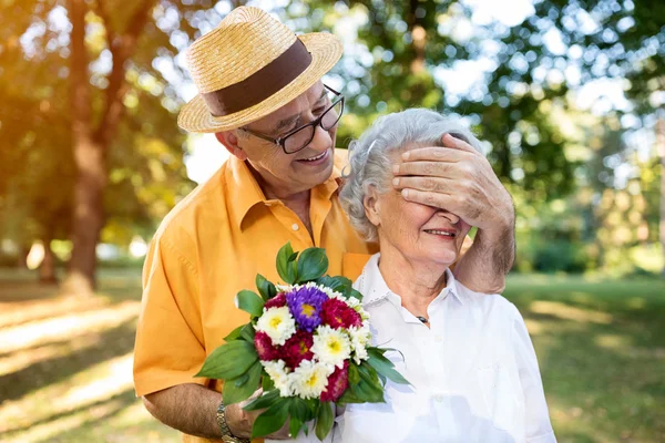 Senior man giving bouquet of colored flowers to his wife Stock Picture