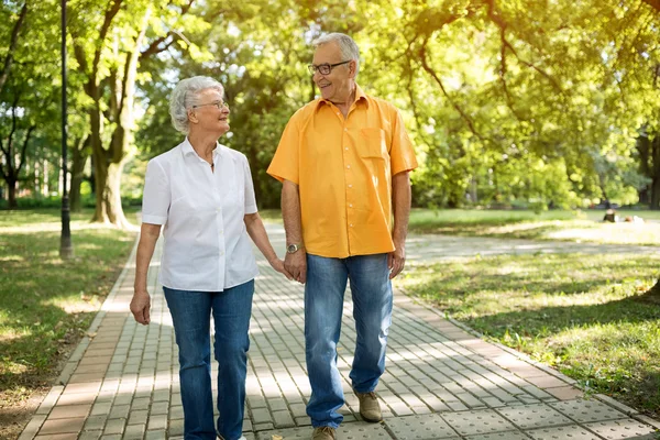 Улыбающаяся пожилая пара, идущая по парку — стоковое фото