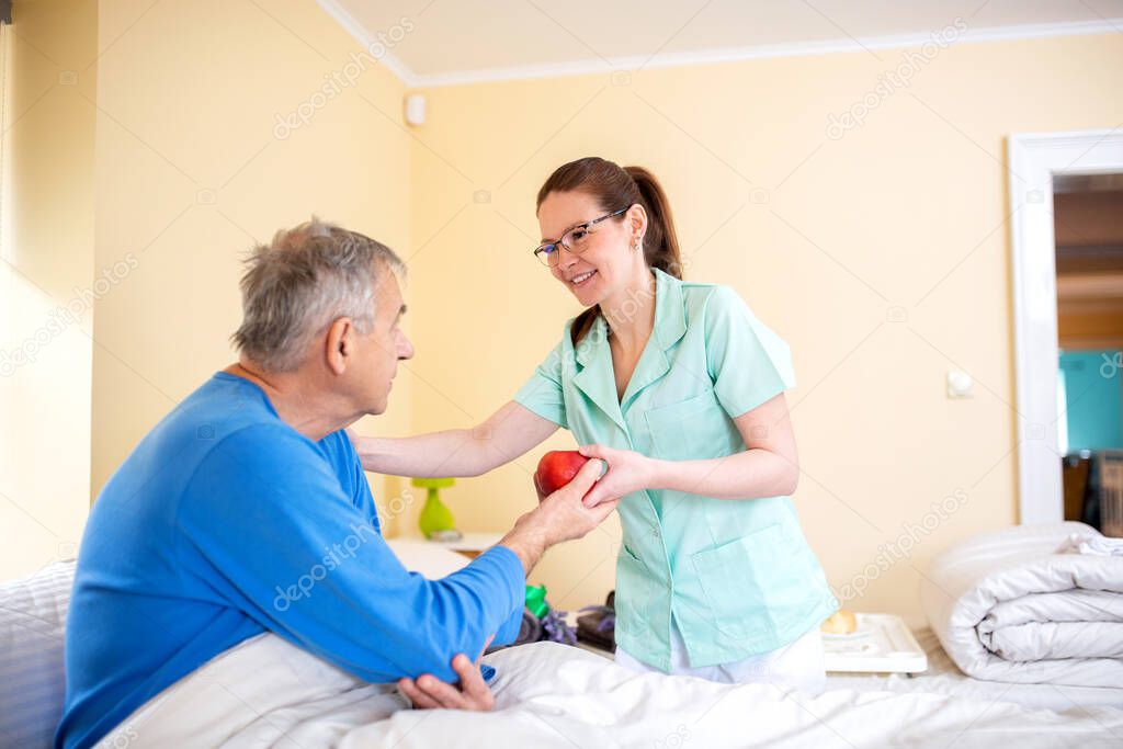 Senior man attended by a nurse in a elder folks home, senior people care concept