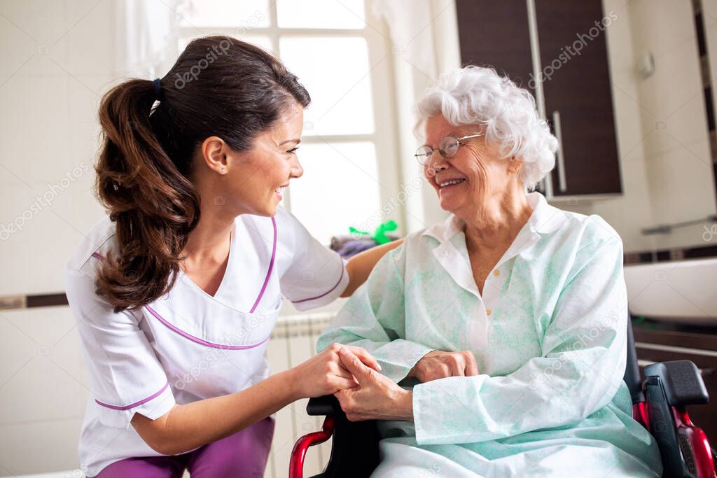 Nurse attending senior woman in a long term care facility, concept of trust between medical staff and home occupants