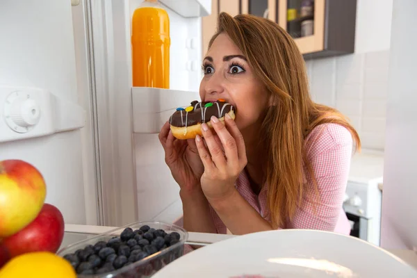 Sugar bonding with a brain of a young woman through the donut and all happening in the fridge, sugar adrenaline concept