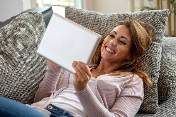Happy Brunette Wanita Berbaring Sofa Dan Memegang Tablet Konsep Menyenangkan — Stok Foto