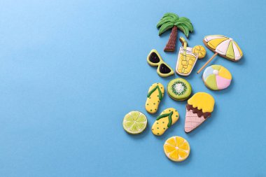 Tropik yaz plaj içeceği süslemeli kurabiyeler, palmiye ağacı, güneşlik, plaj topu, terlikler, dondurma, narenciye, mavi arka plan konsepti.