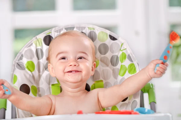 Happy baby eats itself with a spoon and fork — Stock Photo, Image