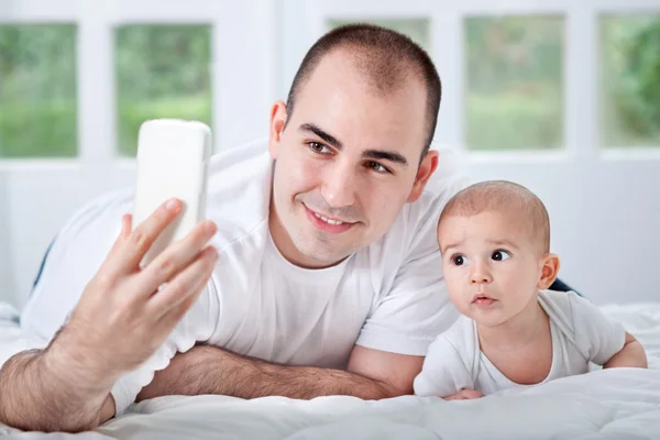 Ojciec i syn patrząc na telefon i biorąc selfie — Zdjęcie stockowe