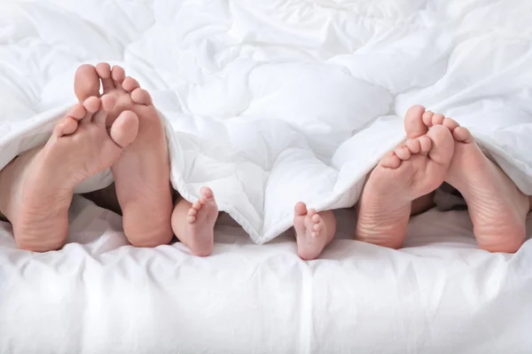 Met baby weergegeven: voet onder de deken (echt) paar — Stockfoto