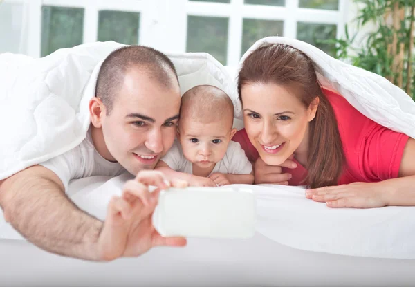 Smiling parents with baby taking family photo — Stock Photo, Image