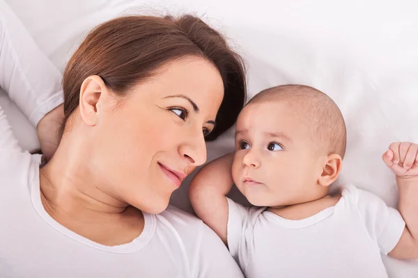 Mor med sin baby avkopplande på sängen — Stockfoto