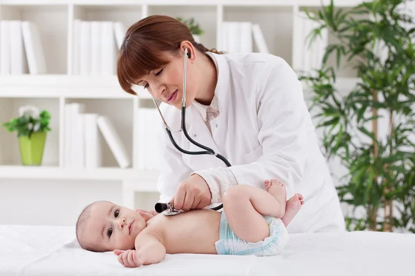 Jovem médico fêmea examinando um bebê paciente — Fotografia de Stock