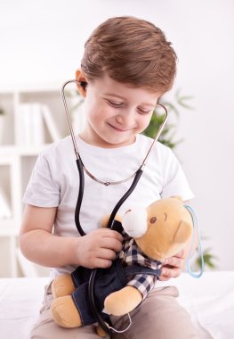 Çok güzel çocuk oyuncak ayı inceleyerek doktor stetoskop ile 