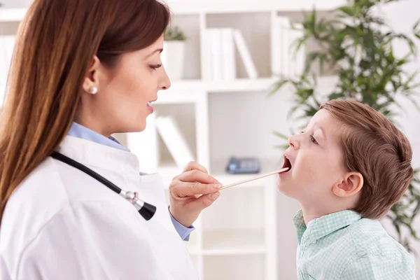 Sonriente médico joven examinando garganta a niño paciente — Foto de Stock