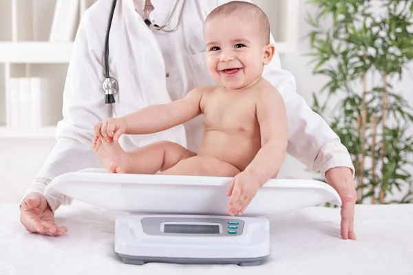 Happy smiling baby in pedrician office, measuring weight — Stock Photo, Image