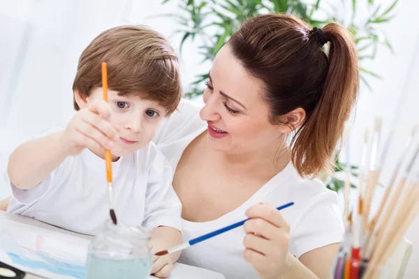 Jonge mooie aantrekkelijke moeder leert haar kind te schilderen — Stockfoto