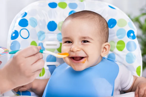 フルーツ マッシュ ポテトを食べて笑顔の幸せな愛らしい赤ちゃん — ストック写真