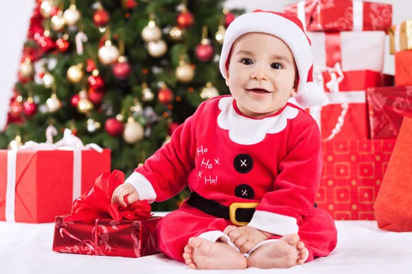 Happy cute smiling little santa claus baby with gifts and christ — Stock Photo, Image