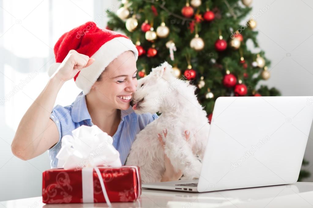 Happy smiling girl and dog using compute and buy presents for christmas