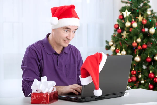 Zaskoczony, człowiek starszy Świętego Mikołaja za pomocą komputera — Zdjęcie stockowe