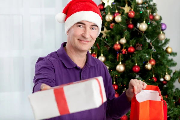 Homme âgé avec casquette Santa donne un cadeau pour Noël — Photo