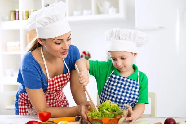 부엌에서 상 추를 준비 하는 어머니와 요리사의 모자와 아들 — 스톡 사진