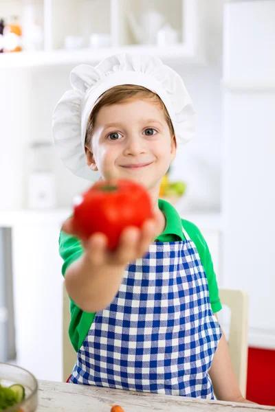 Anak kecil yang lucu dengan topi masak memegang tomat — Stok Foto