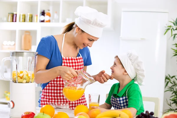 母亲带着健康的橙汁和她快乐的小孩 — 图库照片