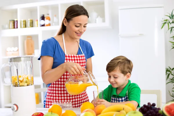 Ibu muda dan anak menyiapkan jus buah — Stok Foto