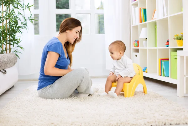 Hermosa madre aprendiendo niño pequeño cómo sentarse en el orinal —  Fotos de Stock