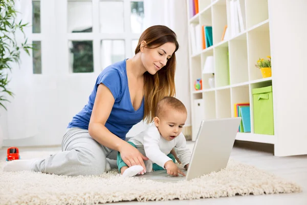 Jovem mãe atraente e bebê usando o computador — Fotografia de Stock