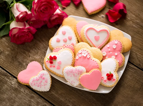 Bela saborosa dia dos namorados biscoitos na placa e rosas — Fotografia de Stock
