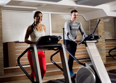 Gençler kardiyo yaparak spor salonunda egzersiz makinesi üzerinde