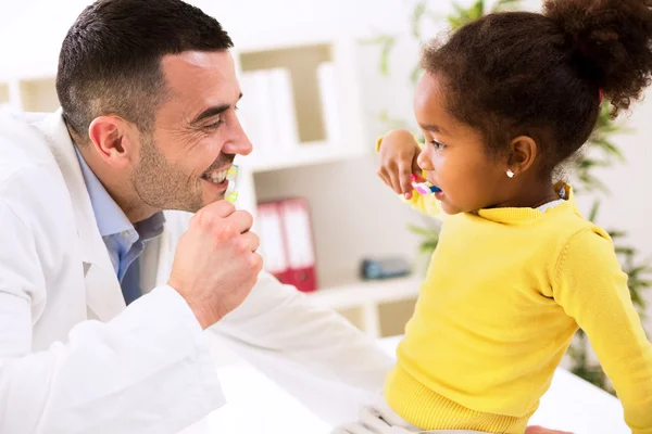 Especialista pediatra muestra al niño cómo cepillarse los dientes —  Fotos de Stock