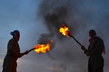 Irak 'ın Akre kenti yakınlarındaki Nowruz / Novruz kutlamaları sırasında iki tanınmayan adam, yerel bir gelenek olan Irak' ta, insanlar dağların zirvesine meşale taşıyorlar.