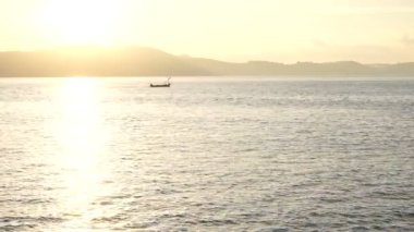 Adanın arka planında sabah denizde küçük bir tekne.