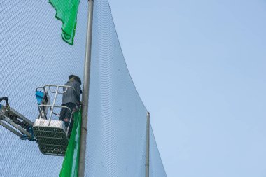 İnşaat alanındaki işçi vince ağ takıyor.