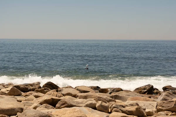 Tembel bir yaz öğleden sonrasında yumuşak bir deniz kayalıklarda kırılan küçük dalgalar ve zevk için avlanan bir dalgıçla