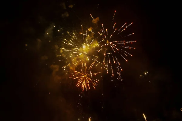 Siyah arka plan gökyüzüne karşı havai fişek patlaması ve renkli duman izleri.