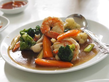 Büyük, yassı, karides ve lahana soslu, beyaz tabakta kızarmış şehriye.