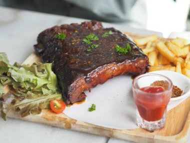 Domuz pirzolası, barbekü domuz pirzolası, patates kızartması sebze salatası, domates sosu, ahşap tepside temiz bir bardak, yiyecek.