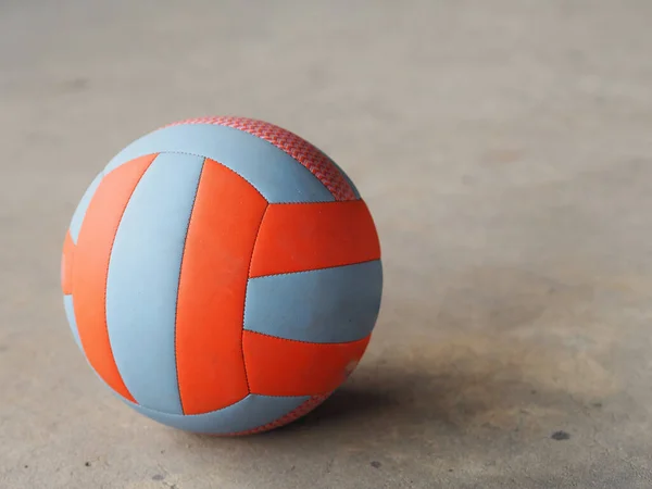 volley ball placed on the concrete ground, blue and orange color, sport