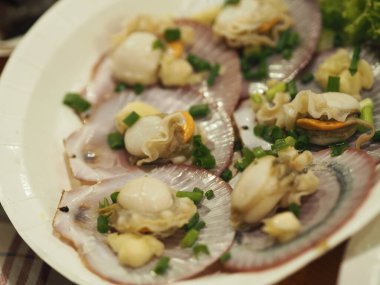 Taze soğanlı buğulanmış midyeler beyaz tabakta doğranmış soğanlar, kabuklu deniz ürünleri.