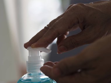 Eline jöle damlatan kadın jöle tutan el dezenfektanı, jelatin ile saf plastik şişeyi karıştıran pompalı kadın bulaşıcı Corona virüsünü, covid-19 virüsünü korumak için kirli çamaşır yıkama makinesini iten kadın.