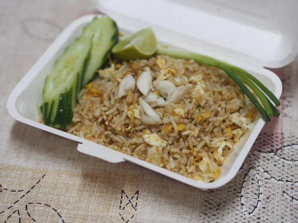 Crab meat fried rice topped with Scrambled egg, style Thai food in white paper box read to eat