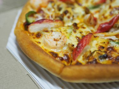 Üstünde karides, yengeç çubuğu, jambon, ananas ve sos karton kutuda.