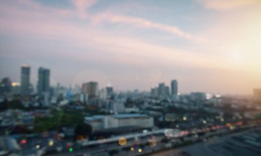 Bir binanın penceresinden geçen bulanık manzara şehir manzarasını ve arka planda ışık olan şehir manzarasını gösteriyordu; modern bir şehir manzarası.