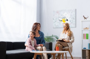Anne psikoloğu ziyaret ederken kızını kucaklıyor.