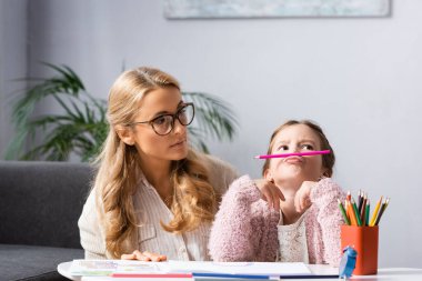 little girl fooling while drawing pictures at psychologist clipart